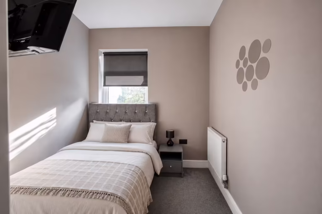 Cosy bedroom with bed, window and wall art.