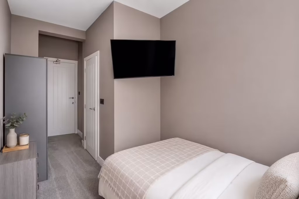 Modern bedroom with wall-mounted TV and neutral decor.