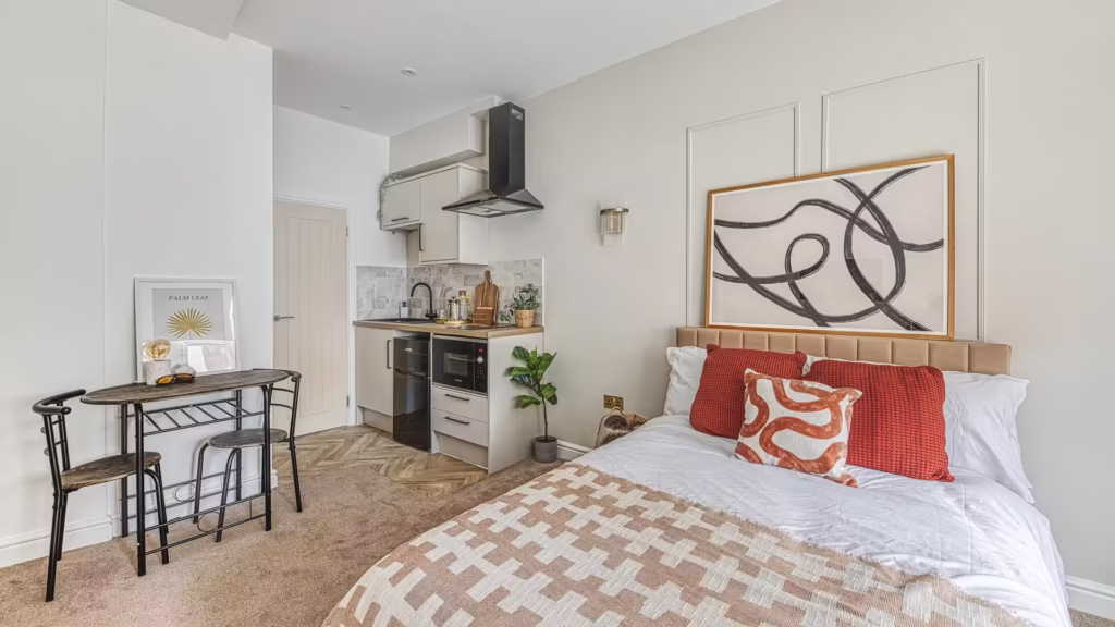 Modern studio apartment interior with kitchenette and bed.