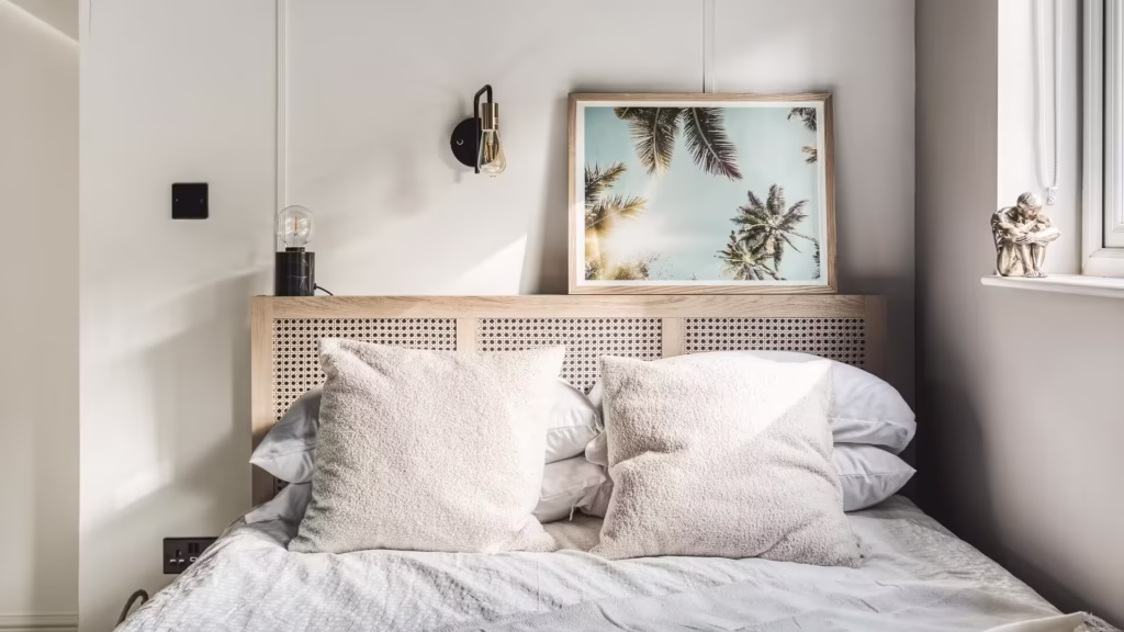 Cosy bedroom with framed palm print and pillows.