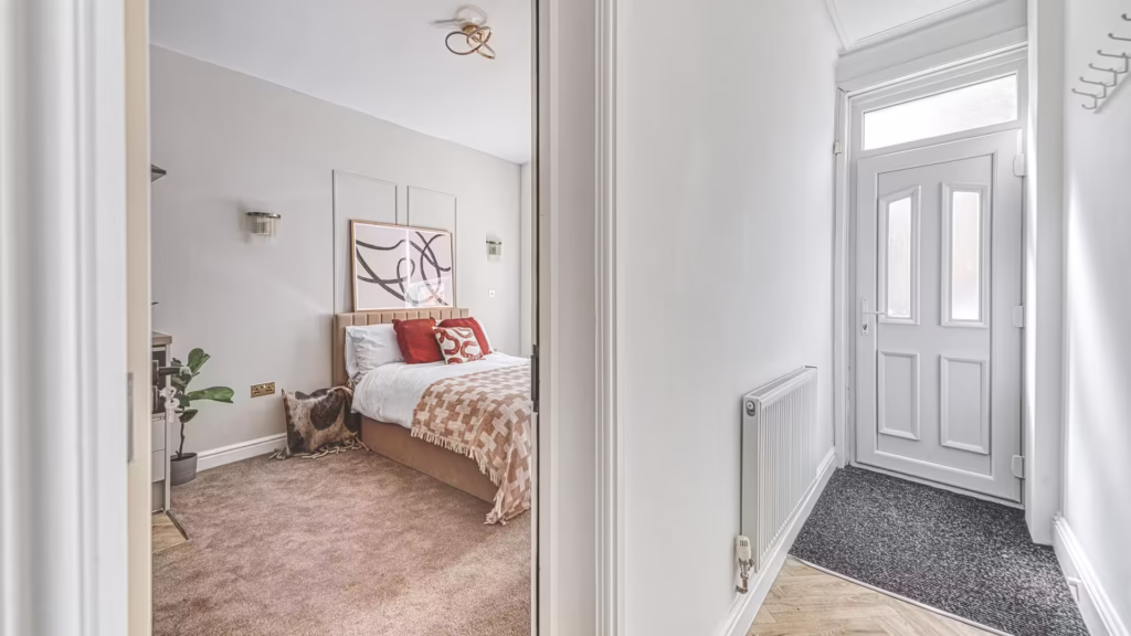 Bright bedroom with modern decor and front door view.